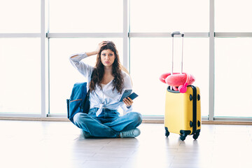 Confused Woman Sitting in Airport Terminal with Luggage and Phone Appears Frustrated While Waiting...