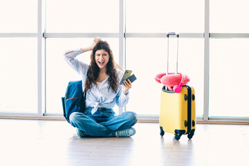 Young woman in casual outfit upset at the airport holding a phone beside luggage and accessories in...