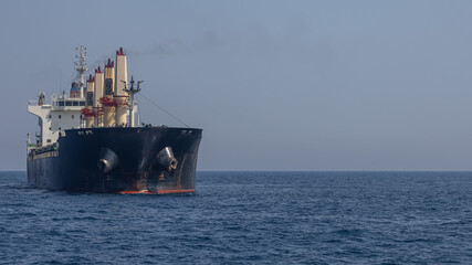 A large marine vessel transports cargo on the high seas. Navigation of large ships. A large cargo ship at sea. Smoke is coming out of the chimney of a marine vessel.