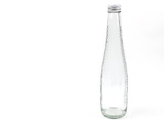 Empty clear glass bottle with textured design and metal cap on white.