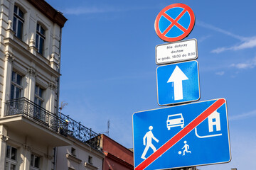 Stacked European road signs clearly regulate urban traffic flow, showing a no parking zone with...