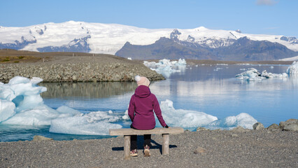 A visitor enjoys the tranquil atmosphere at Jokulsarlon Glacier Lagoon, surrounded by floating...