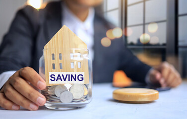 Saving money concept with businessman working on the table and jar to collecting a coin and put a...