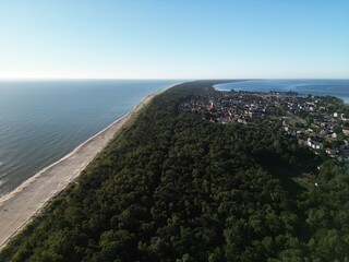 Aerial panoramic view of densely forested coastal peninsula with residential area overlooking azure...
