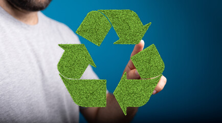 Sustainable concept image showing a person interacting with a recycling symbol made of grass.