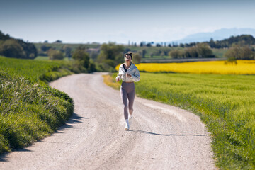 Obraz premium Sporty woman running through the countryside