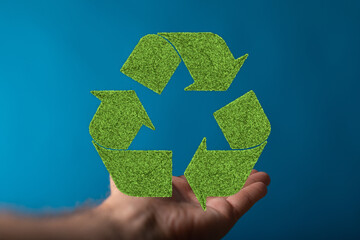 Eco-friendly recycling concept.  Hand holding a green recycling symbol.