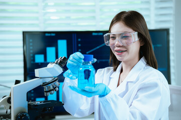 Fototapeta premium A female scientist conducts research in a modern laboratory, wearing protective gear, analyzing blue liquid in test tubes, focusing on innovation, discovery, accuracy, and medical development.