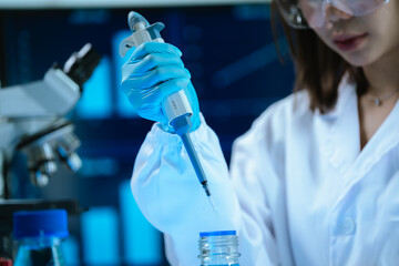 A female scientist in a modern laboratory conducts research using a pipette and microscope, analyzing samples under blue light to develop medical innovations and scientific discoveries.