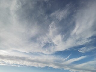 Dramatic white clouds swirling across blue sky creating natural abstract patterns in daylight
