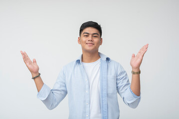 Smiling Southeast Asian young man with open arms raised, wearing casual blue shirt and white tee, expressing a warm and hospitable vibe.
