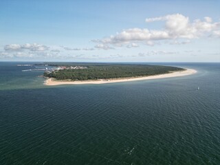 Aerial view of curved sandy peninsula extending into deep blue ocean waters