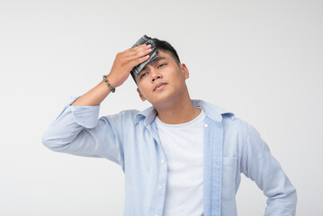 Young Filipino man wipes sweat from his forehead with handkerchief, showing signs of heat, dismay,...