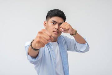 Bold young Filipino man throws fist toward camera in a strong, confident pose with focused, intense...