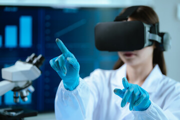 A female scientist wearing virtual reality goggles explores interactive data and medical...