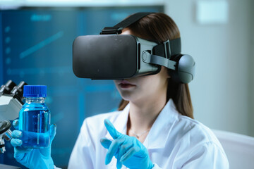 A female scientist wearing virtual reality goggles explores interactive data and medical...