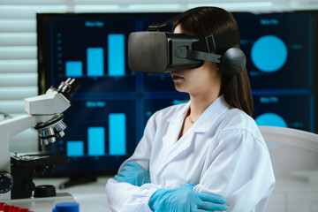 A female scientist wearing virtual reality goggles explores interactive data and medical...