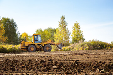 Yellow bulldozer at a construction site. Big wheel excavator leveling and clearing the land plot...