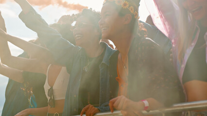 Audience With Colored Smoke Behind Barrier Dancing And Singing At Outdoor Festival Enjoying Music