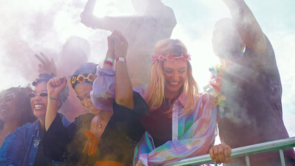 Audience With Colored Smoke Behind Barrier Dancing And Singing At Outdoor Festival Enjoying Music