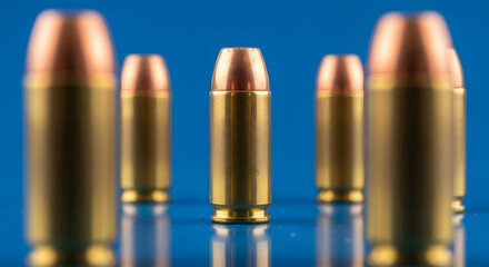 Ammunition Bullets with Copper and Brass Casings on Reflective Surface in Blue Background