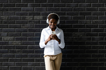 Smiling African woman using smart phone and listening to the music.