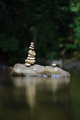 Spa stones are arranged vertically on a stream, natural blurred background, vertical image.