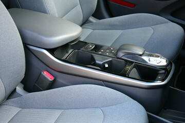 New electric car armrest. Close up Lux electric car automatic transmission. Electric Car inside, driver and passenger seats, cup holders and armrest. Premium Electric Car interior.