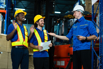 Smiling warehouse workers and supervisor engaging in friendly discussion while reviewing logistics...