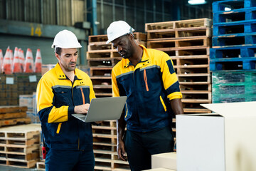 African and asian adult male warehouse workers collaborating with laptop for inventory process near...