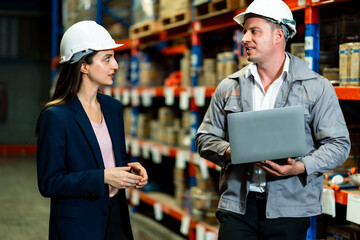White adult female logistics manager discussing tasks with white adult male warehouse worker...