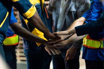 A diverse group of warehouse workers, including both white and black men, hold hands, demonstrating unity, teamwork, strength, and cooperation within the industrial workplace., logistics warehouse.