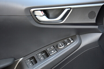 Window control buttons in lux electric car. Car interior details of door handle with windows controls, Speaker and adjustments. Modern premium electric car interior details.