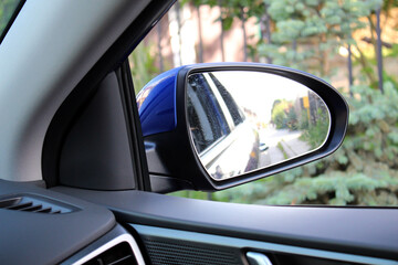 Blue Rearview car driving mirror. Side rear-view mirror on a modern car.  Look in the rear view mirror of a car. Accessory for vehicles to look back on road for good visibility and drive car safely.