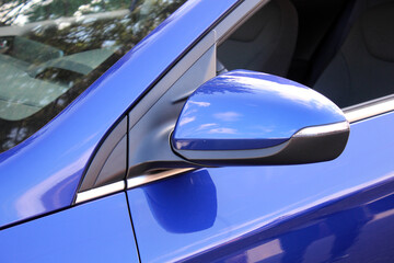 Blue rear view mirror of electric car. Side rear view mirror on a modern new car. Electric car rear view mirrors close up .