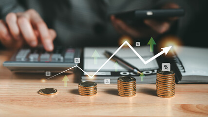 Stacks of coins and an upward graph overlay highlight financial growth, as a hand works on a...