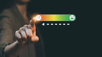 Hand pointing to sad face on customer satisfaction scale showing low feedback rating concept of...