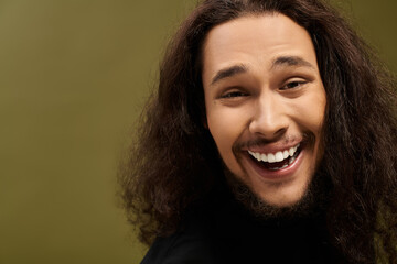 Charming young man with a beard enjoying a joyful moment against a vibrant background
