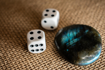 A polished labradorite and two white dice rest on burlap. The contrast of chance and mysticism...