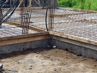 A concrete foundation slab with steel reinforcement bars or rebar at construction site