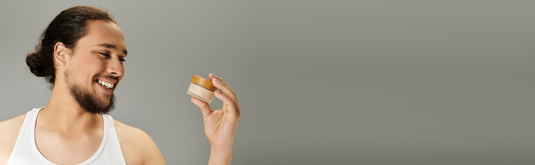 Obraz premium Handsome young bearded man enjoying self care with natural skincare product in a cozy setting