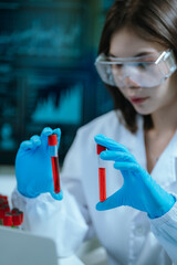 A scientist in a laboratory conducts a medical experiment with a red liquid in a test tube,...