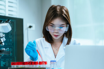 A scientist in a laboratory conducts a medical experiment with a red liquid in a test tube,...