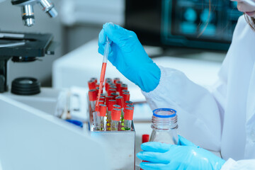 A scientist in a laboratory conducts a medical experiment with a red liquid in a test tube,...
