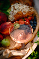 Summer picnic with fresh berries, fruits, almond croissants, and rosé wine on a cozy blanket. Flat lay top view, bright and seasonal outdoor setup.