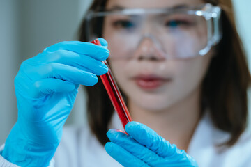 A scientist in a laboratory conducts a medical experiment with a red liquid in a test tube,...