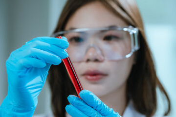 A scientist in a laboratory conducts a medical experiment with a red liquid in a test tube,...