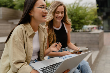 two young pretty women sitting in student campus co-working outside