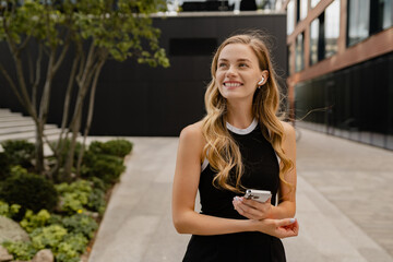 young pretty blond woman walkingoutside in street doing business