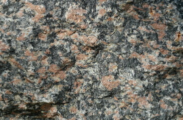 Texture of red-black marbled granite boulder. Natural stone as landscape element. Copyspace.